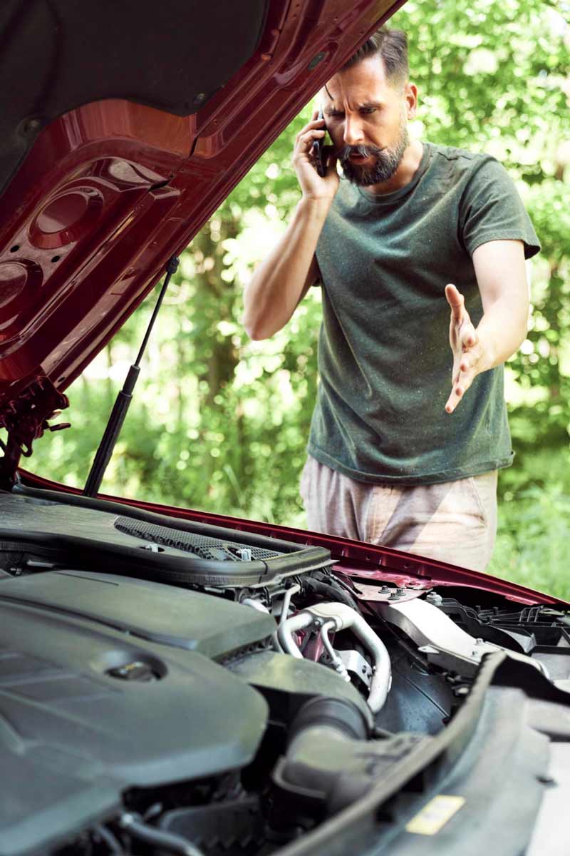 Junger Mann prüft Getriebeschaden bei Schrottauto Ankauf Steinburg